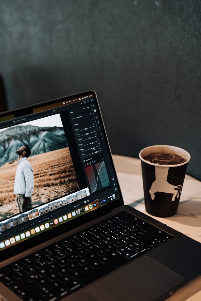 A stylish laptop displaying images sits next to a coffee cup in a cozy café setting.